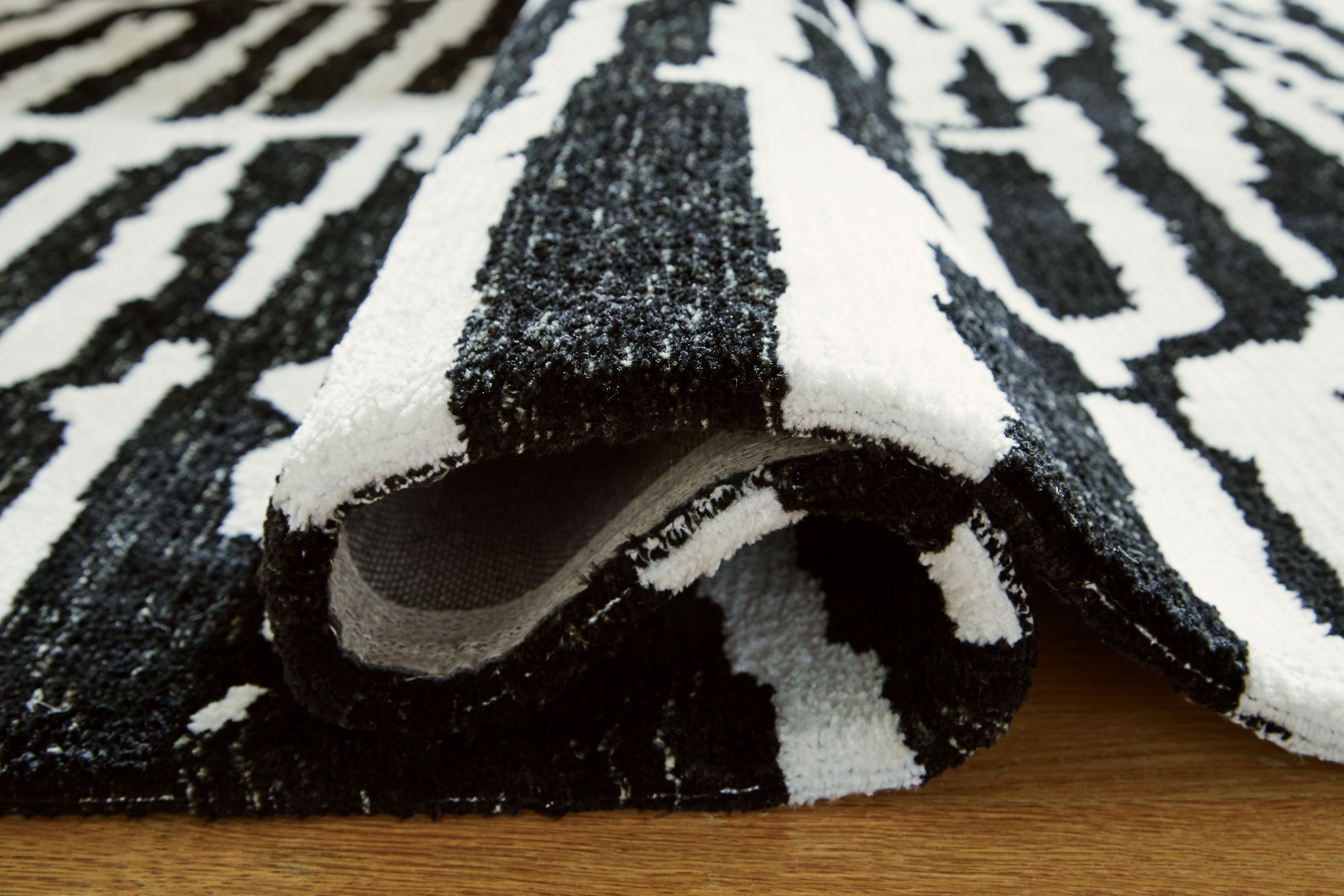 Black-and-white rug edge with rolled texture and short pile