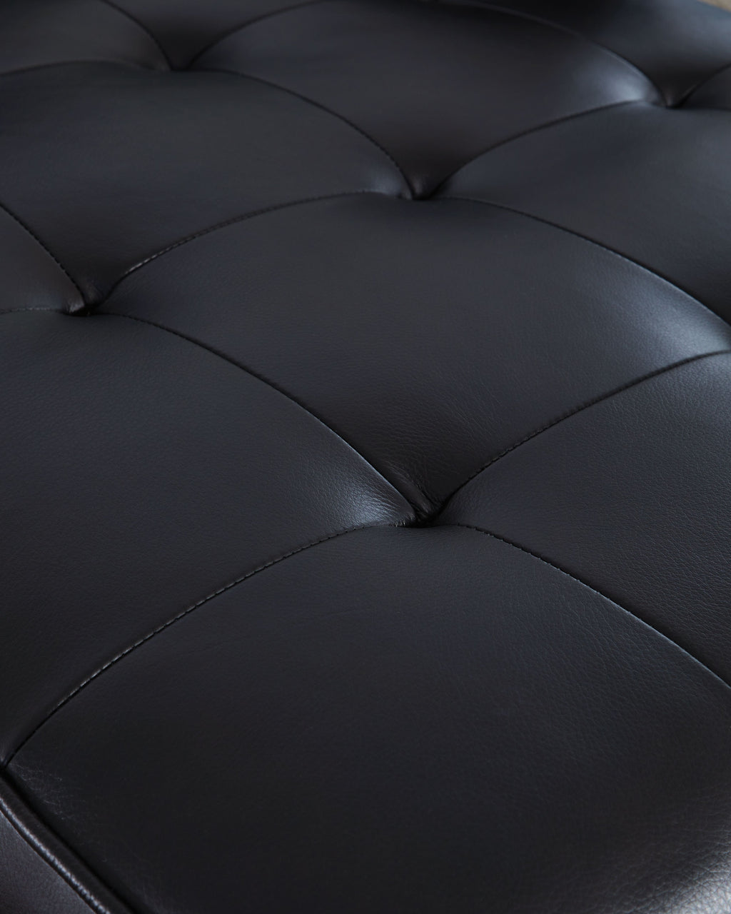 Dark sofa upholstery detail with quilted seam lines across padded cushions
