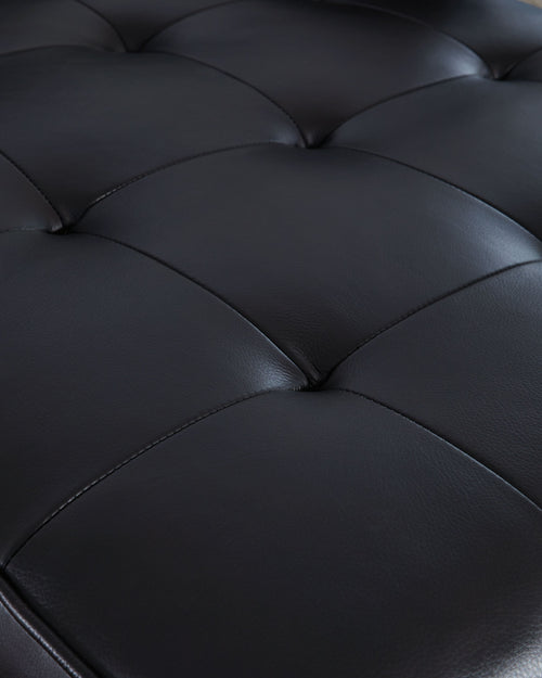 Dark sofa upholstery detail with quilted seam lines across padded cushions