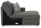 Dark gray corner chaise with rounded arm and patterned throw pillow