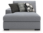 Grey upholstered chaise with back cushions and decorative throw pillows