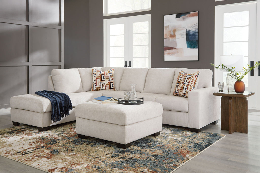 Light beige sectional sofa set with ottoman and patterned throw pillows