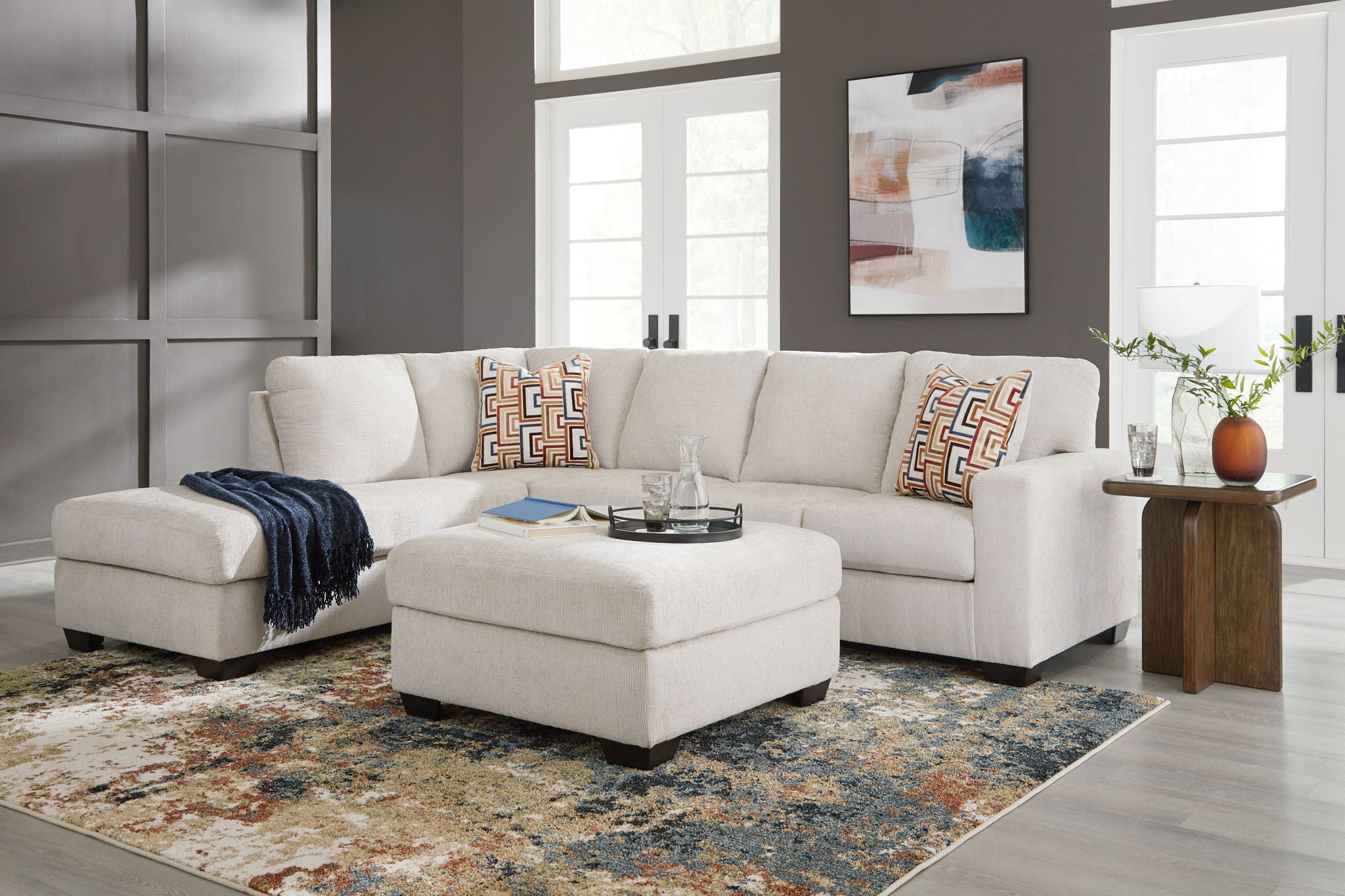Light beige sectional sofa set with ottoman and patterned throw pillows