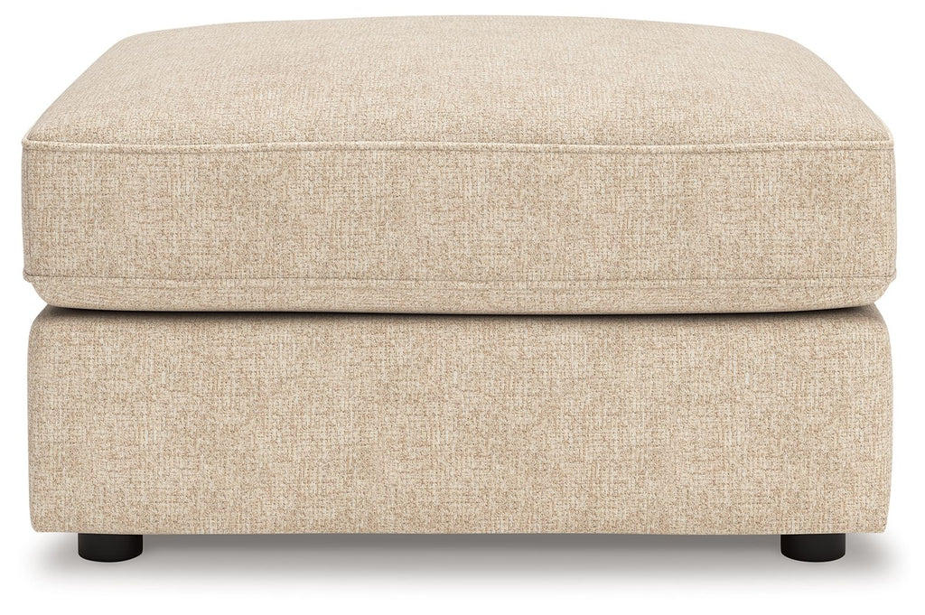 Sand fabric ottoman with low rectangular base, smooth top, and dark legs