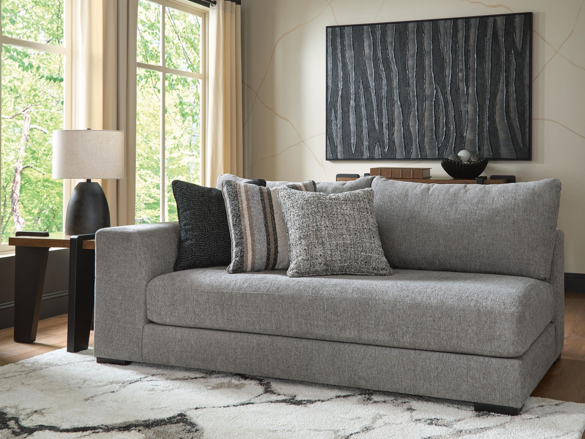 Gray corner chaise with striped throw and three decorative pillows