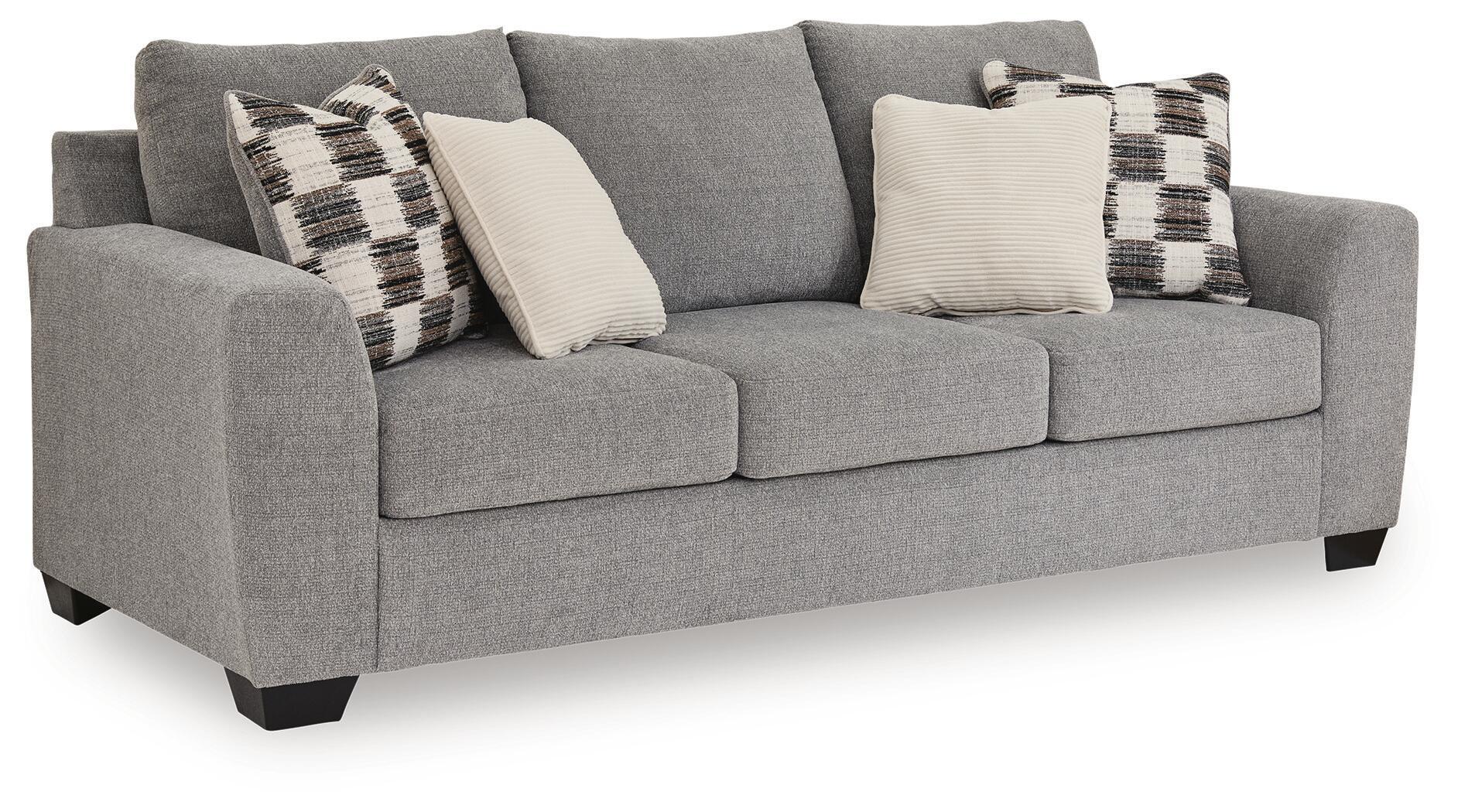 Sofa sleeper, light gray upholstery with plaid and white throw pillows.