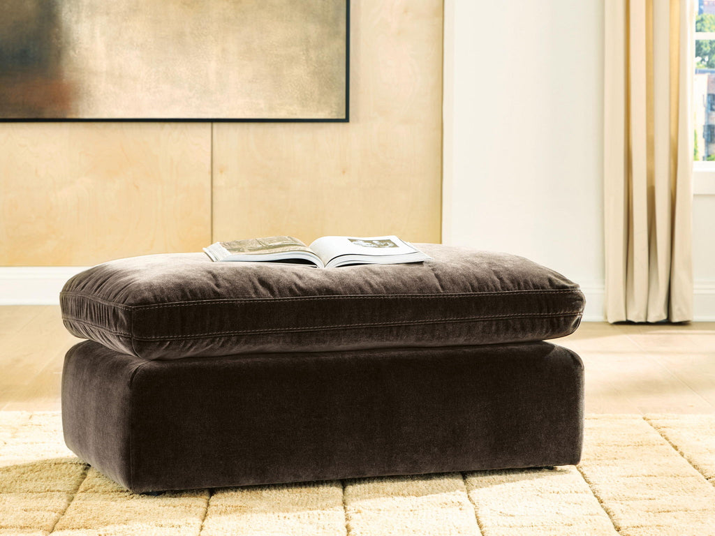 Dark brown cushioned ottoman with round top and tapered legs