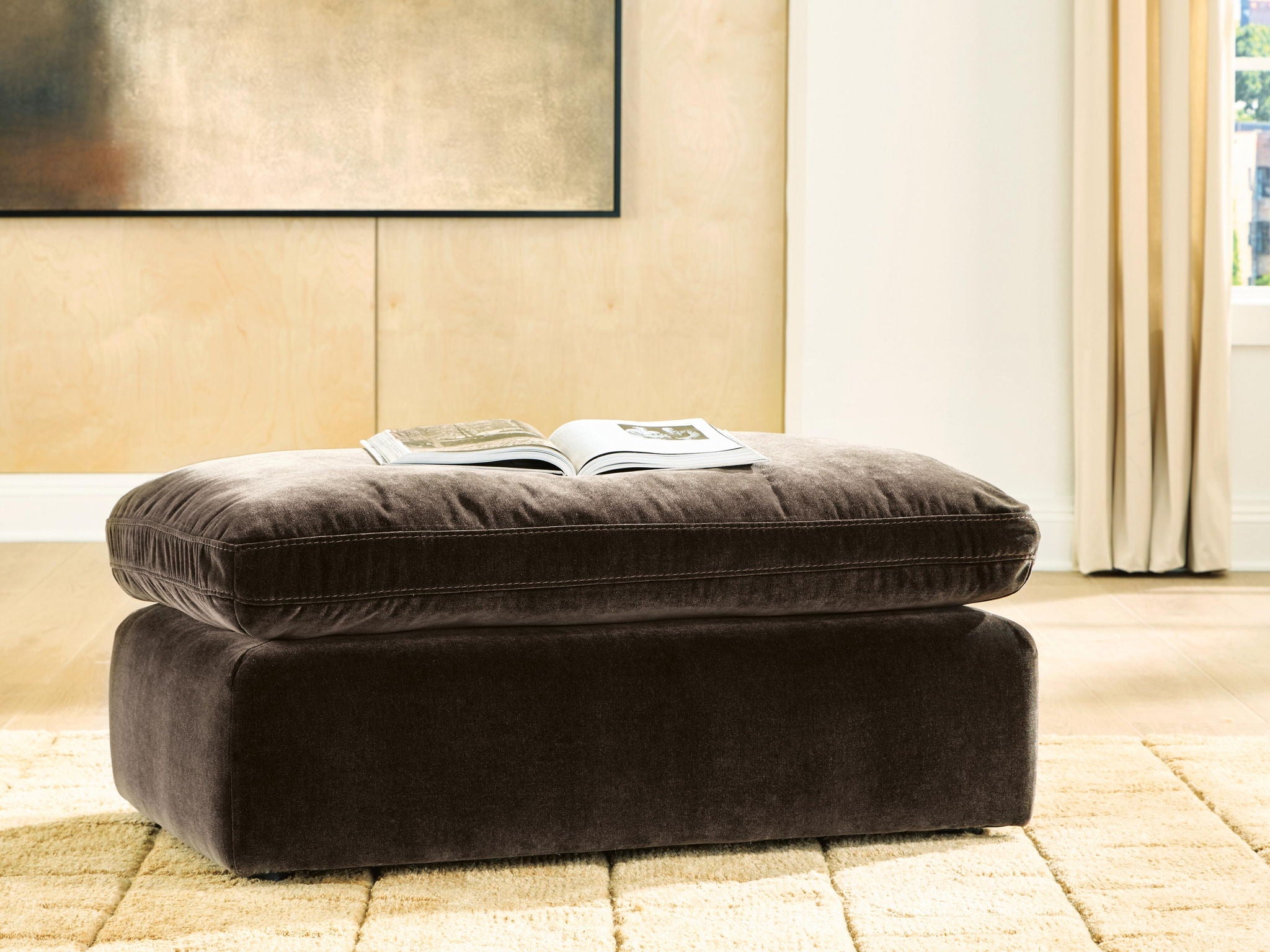 Dark brown cushioned ottoman with round top and tapered legs