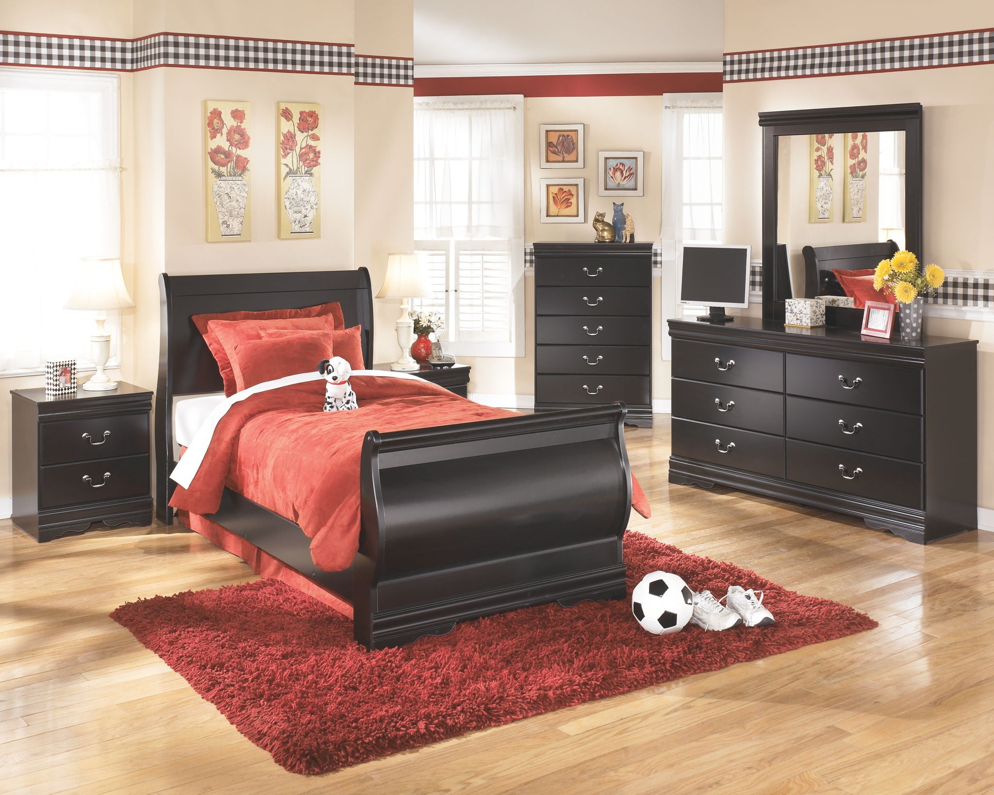 Black dresser with tall mirror and multiple drawers, styled beside bed.