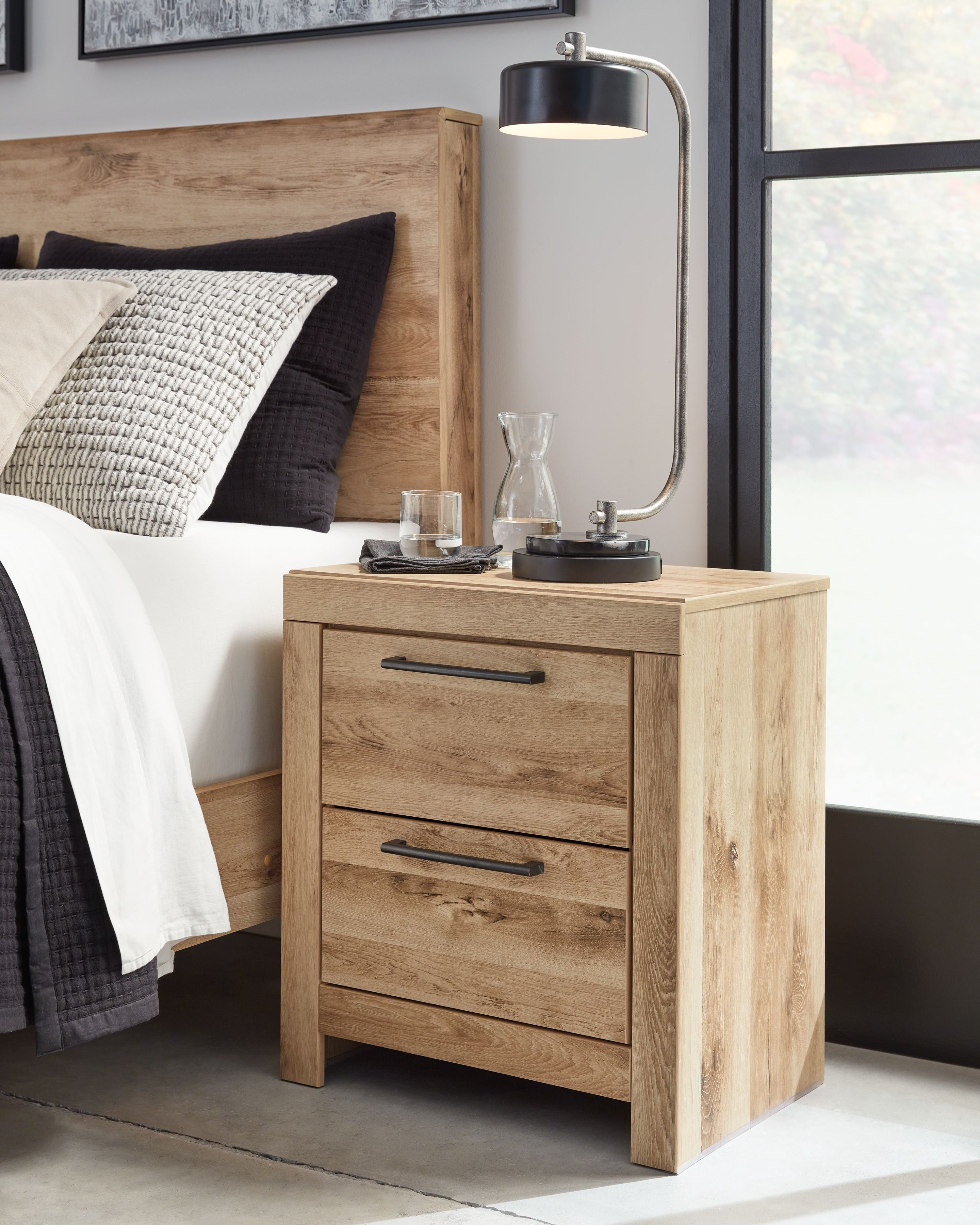 Tan brown two-drawer nightstand with black bar handles, side angle view.