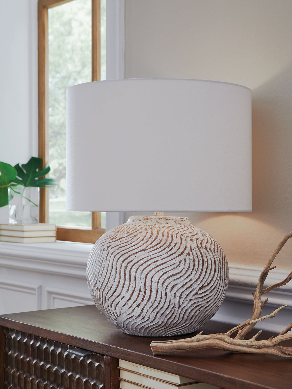 Table lamp with white drum shade on distressed white sphere base with wavy lines