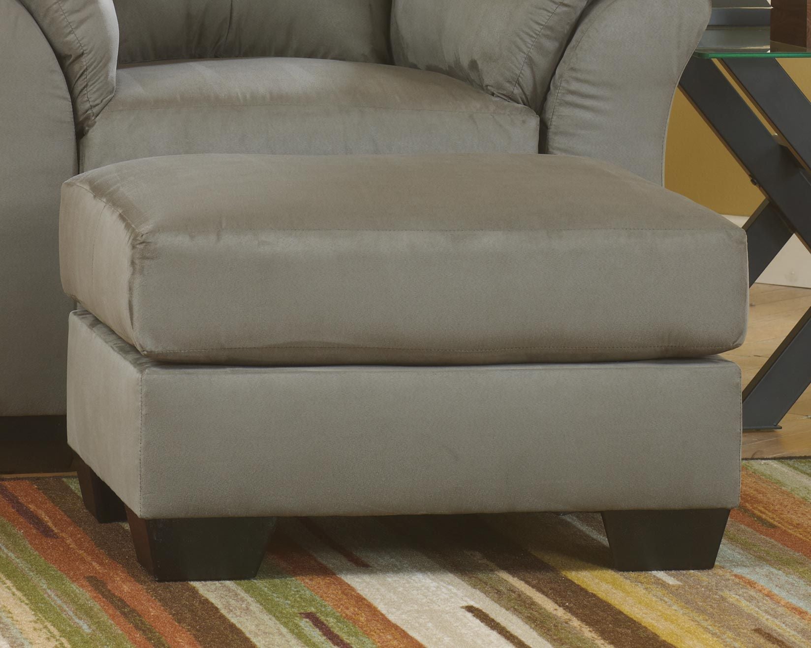 Upholstered ottoman in light gray fabric, padded top and side panels.