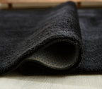 Anaben rug detail: dark pile texture with visible edge stitching
