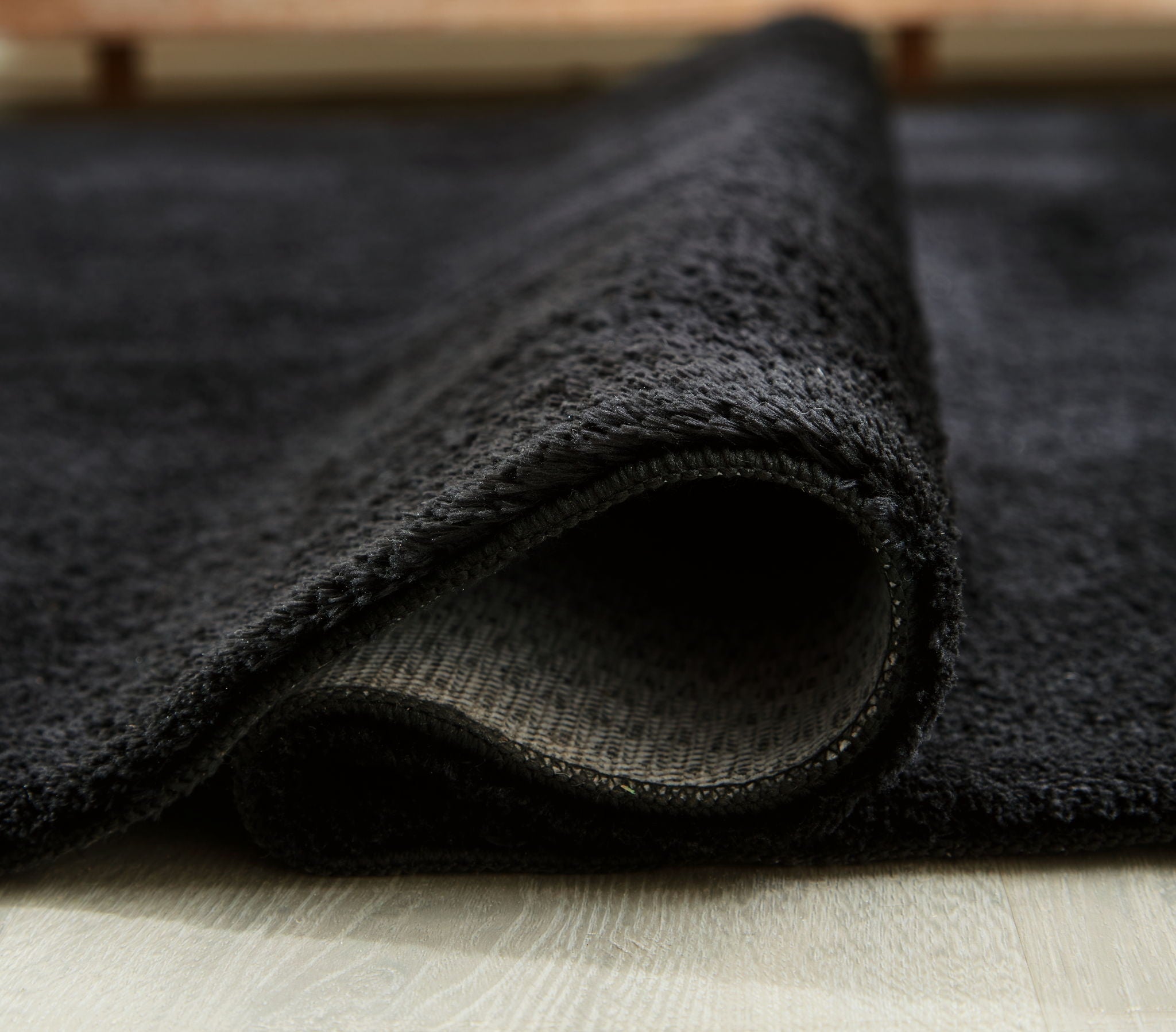 Anaben rug detail: dark pile texture with visible edge stitching