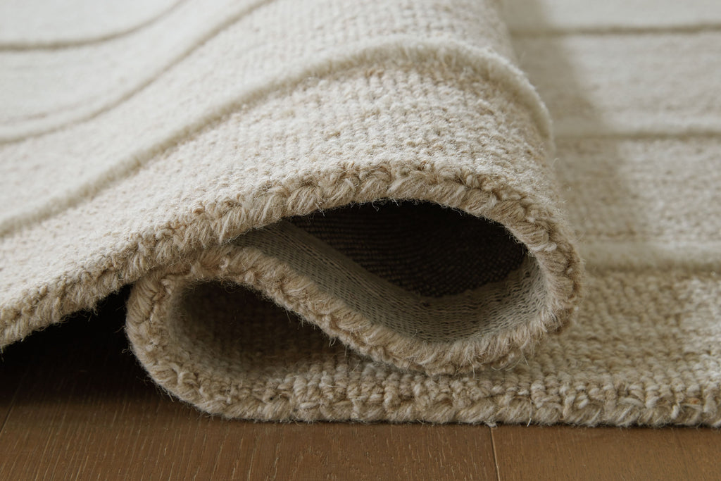 Beige rug edge close-up with folded pile opening and border trim