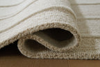 Beige rug edge close-up with folded pile opening and border trim