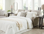 Queen sofa sleeper open for sleeping with white bedding and patterned throw pillows