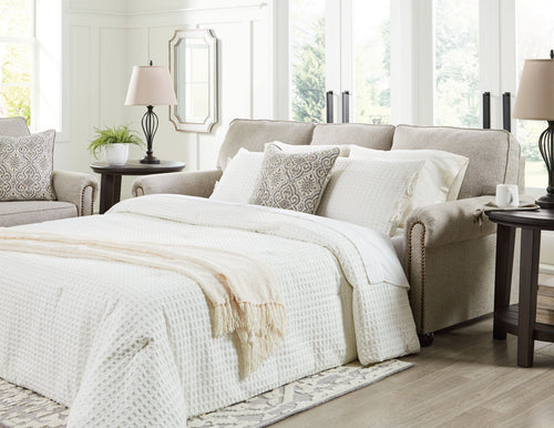 Queen sofa sleeper open for sleeping with white bedding and patterned throw pillows