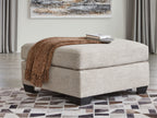 Oversized ottoman with light beige fabric, blocky legs, and a thick cushioned seat.