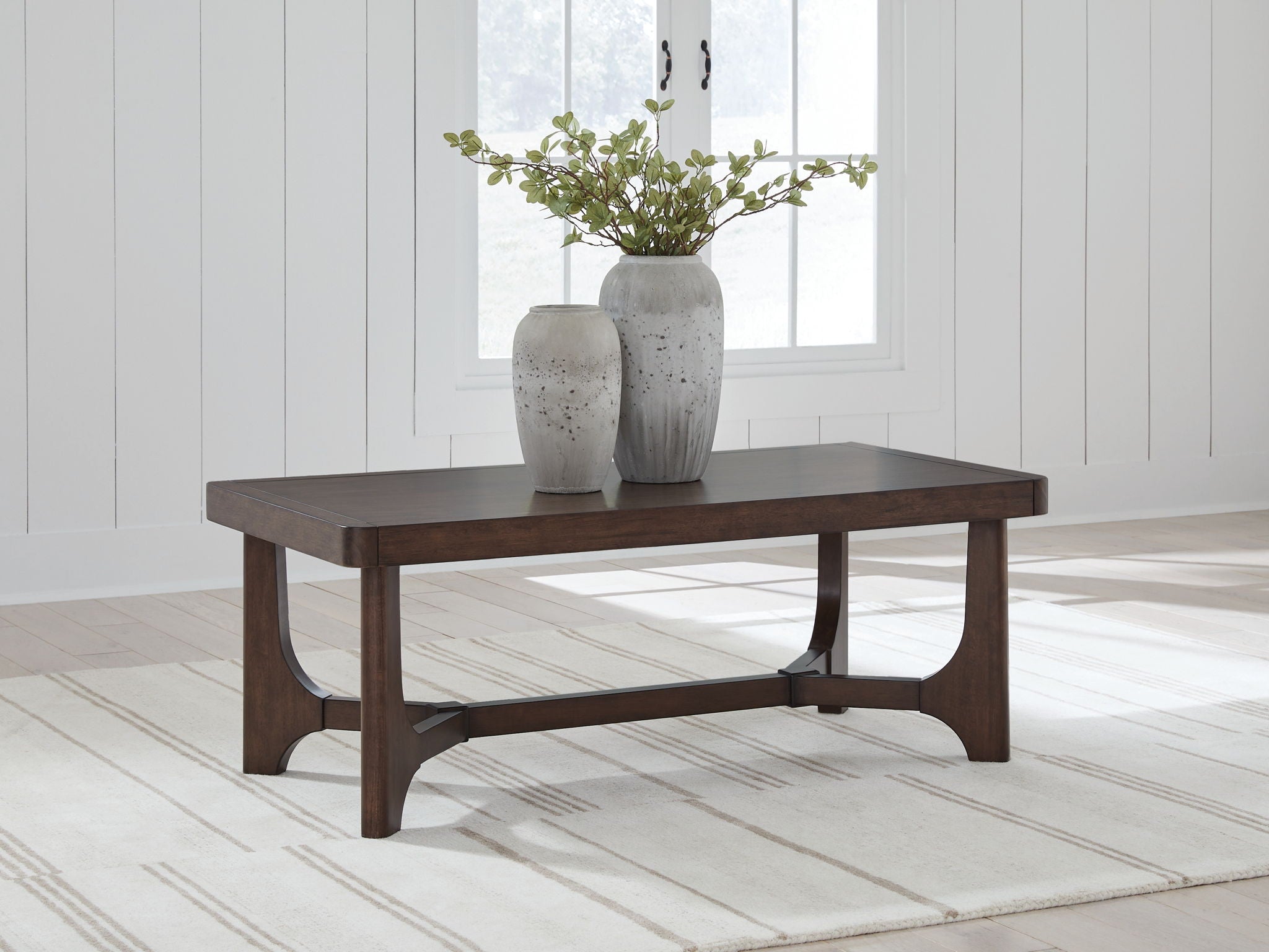 Dark brown rectangular cocktail table with curved apron and sturdy block legs