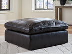 Black oversized accent ottoman with padded seat, rounded top, and low rectangular base