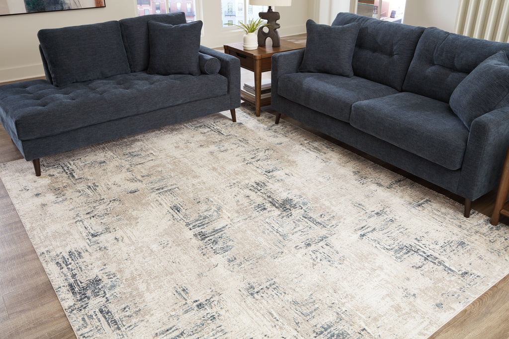 Cream abstract area rug with blue-gray distressed pattern on wood floors.
