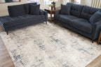 Cream abstract area rug with blue-gray distressed pattern on wood floors.