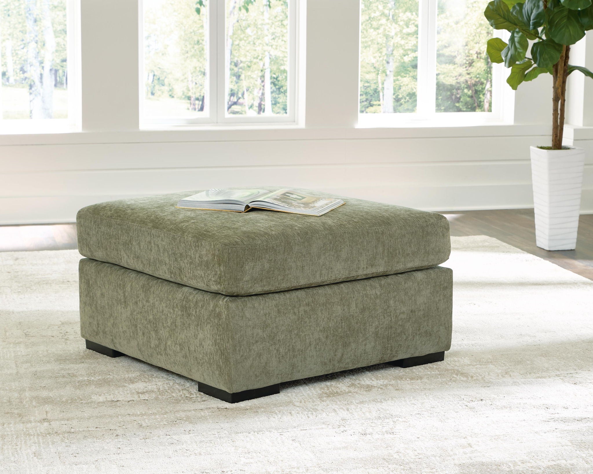 Oversized accent ottoman in green upholstered fabric with square cushioned top and dark legs.