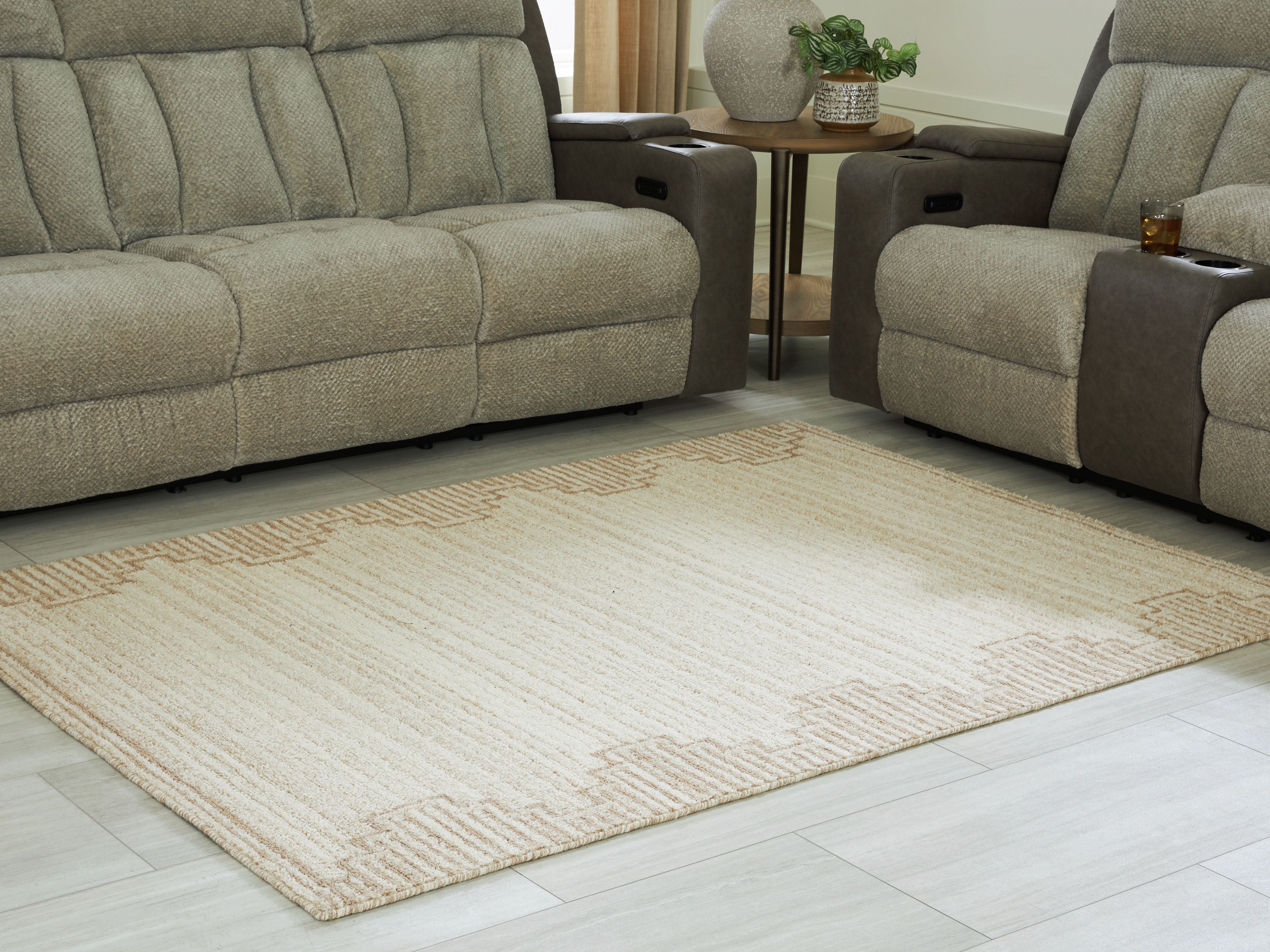 Beige area rug with geometric trim, placed on light wood flooring