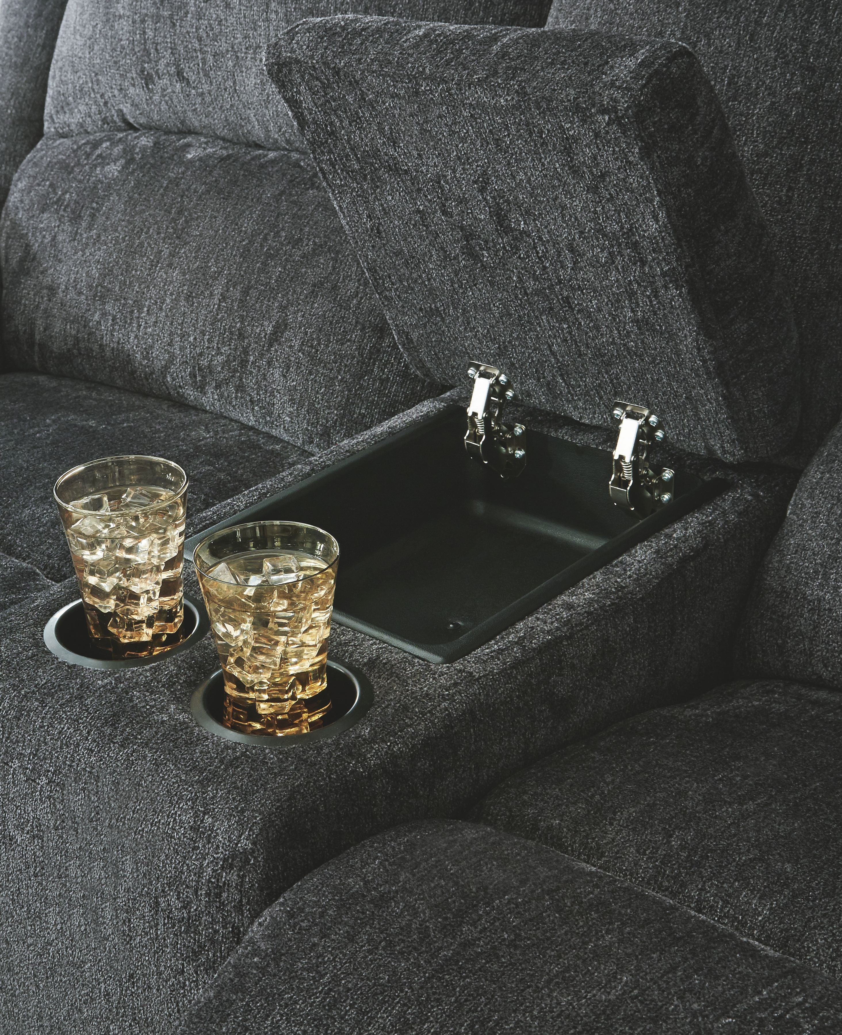 Dark gray reclining loveseat with built-in cup holder tray in the seat