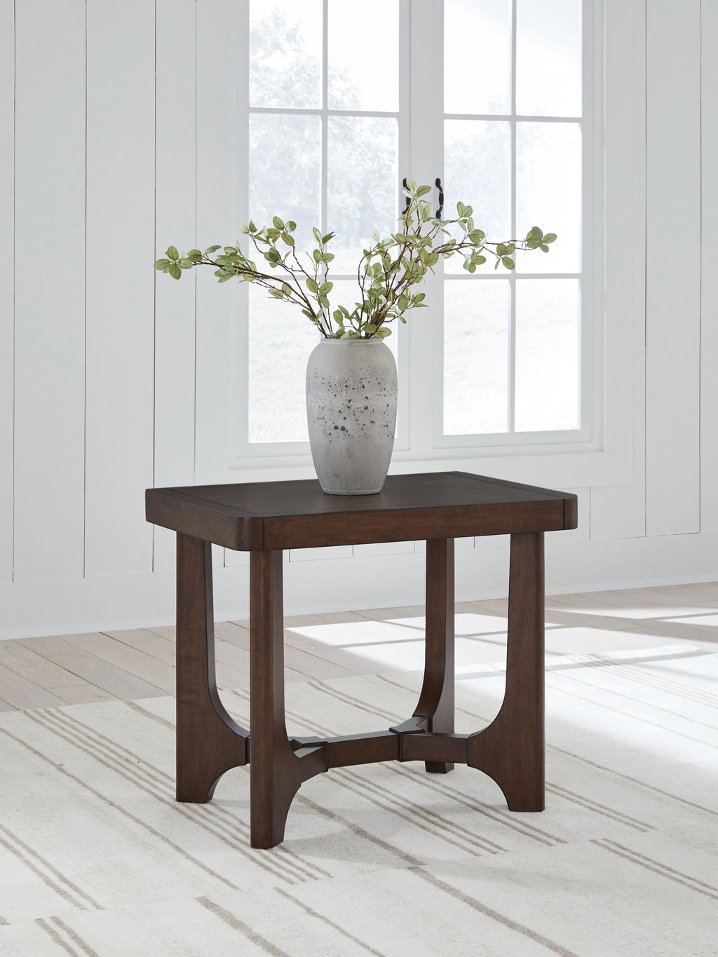 Dark brown rectangular cocktail table with curved apron, shown with a vase on top