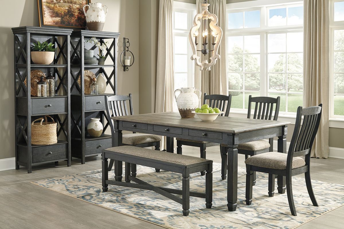Dark gray dining table with two upholstered benches, four slat-back chairs, display cabinet left