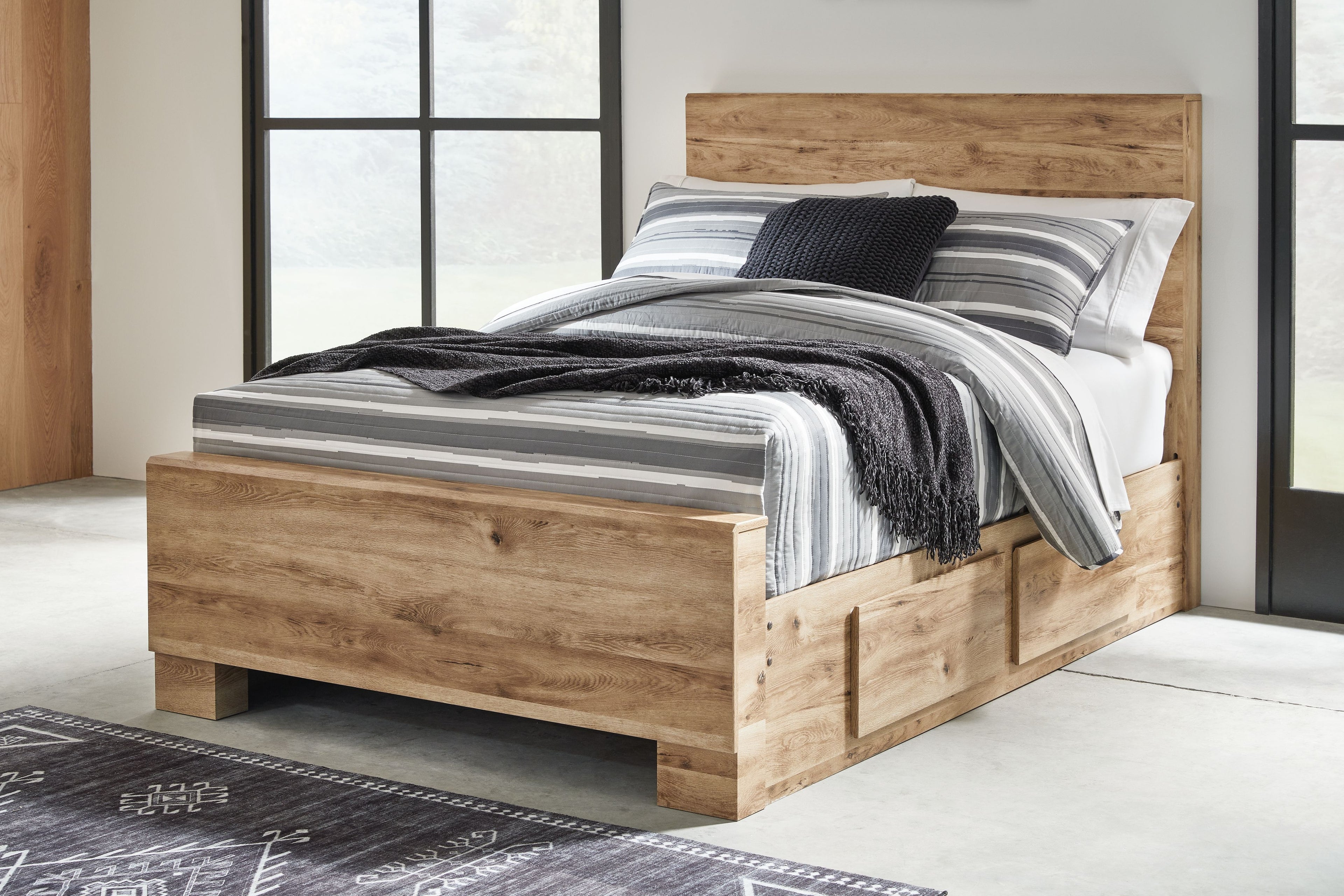 Storage bed with front drawers, light beige wood, black and gray striped blanket on mattress