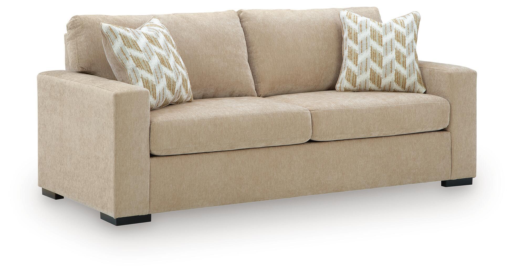Sofa sleeper in light tan fabric with two patterned throw pillows and black feet