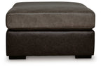 Oversized accent ottoman showing rounded upholstered arms and dark brown base.