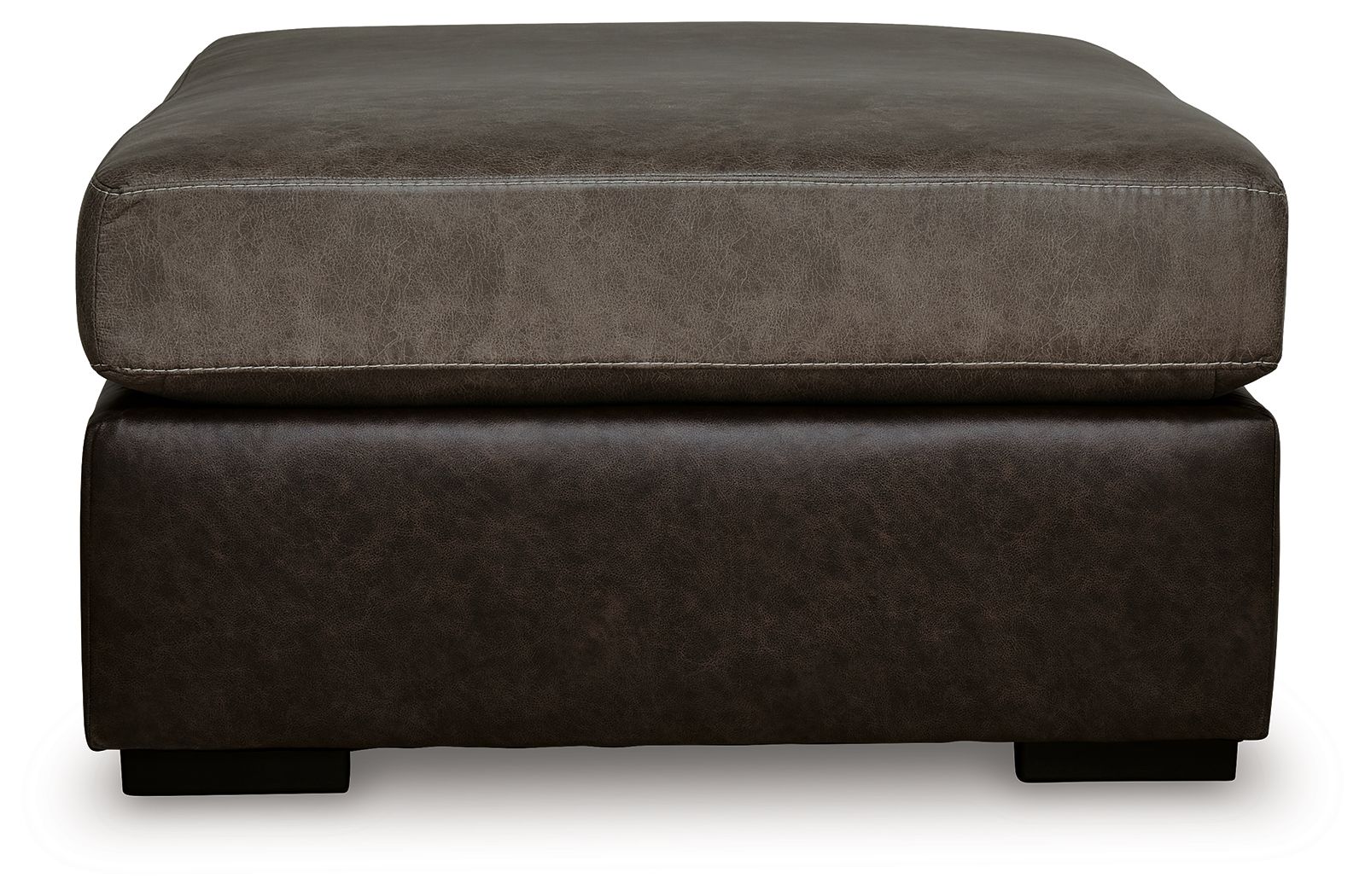 Oversized accent ottoman showing rounded upholstered arms and dark brown base.