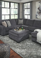 Dark gray sectional sofa with corner chaise and ottoman, patterned accent pillows