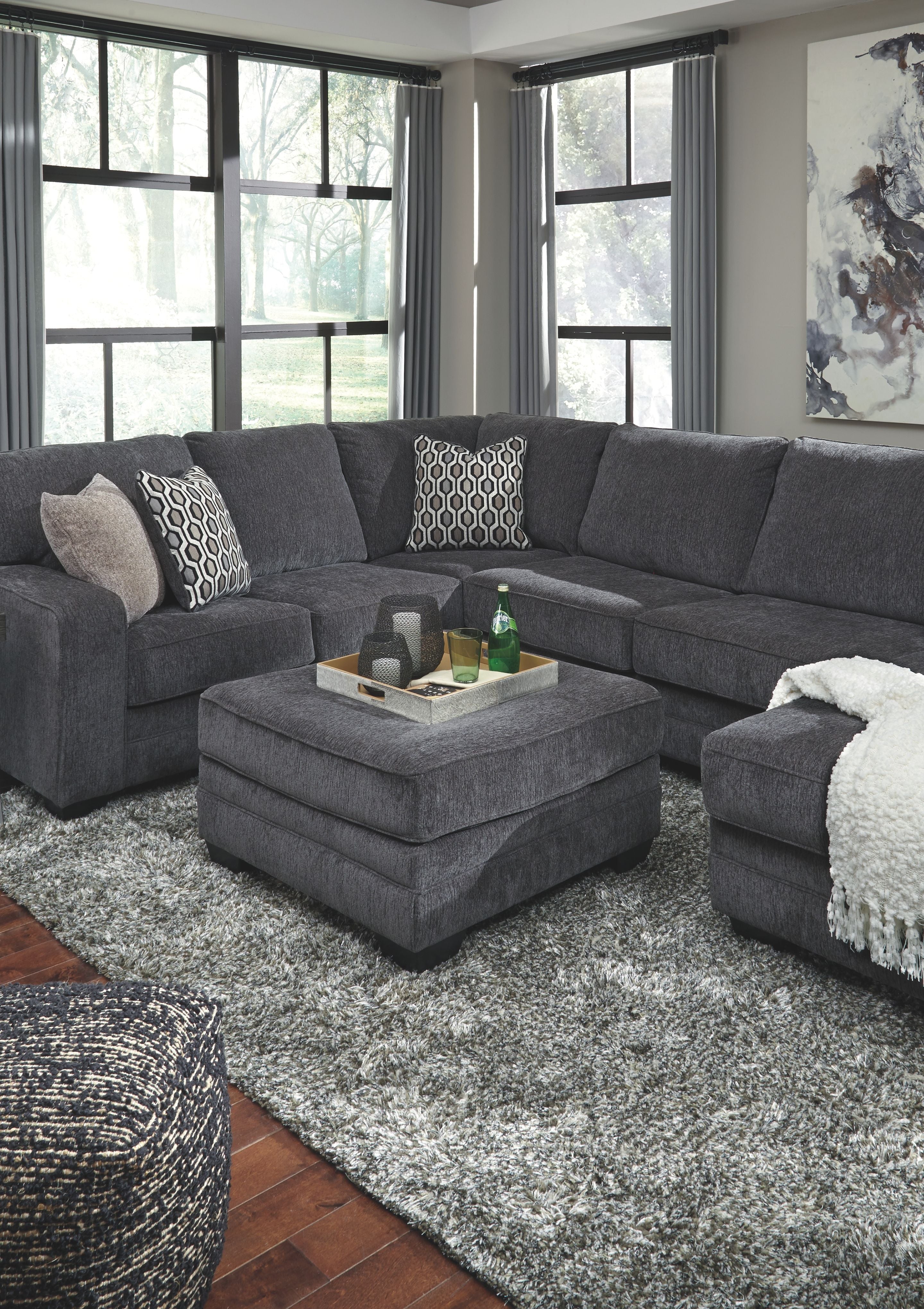 Dark gray sectional sofa with corner chaise and ottoman, patterned accent pillows