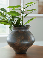Antique brown vase holding green leafy stems, bulbous shape and flared top