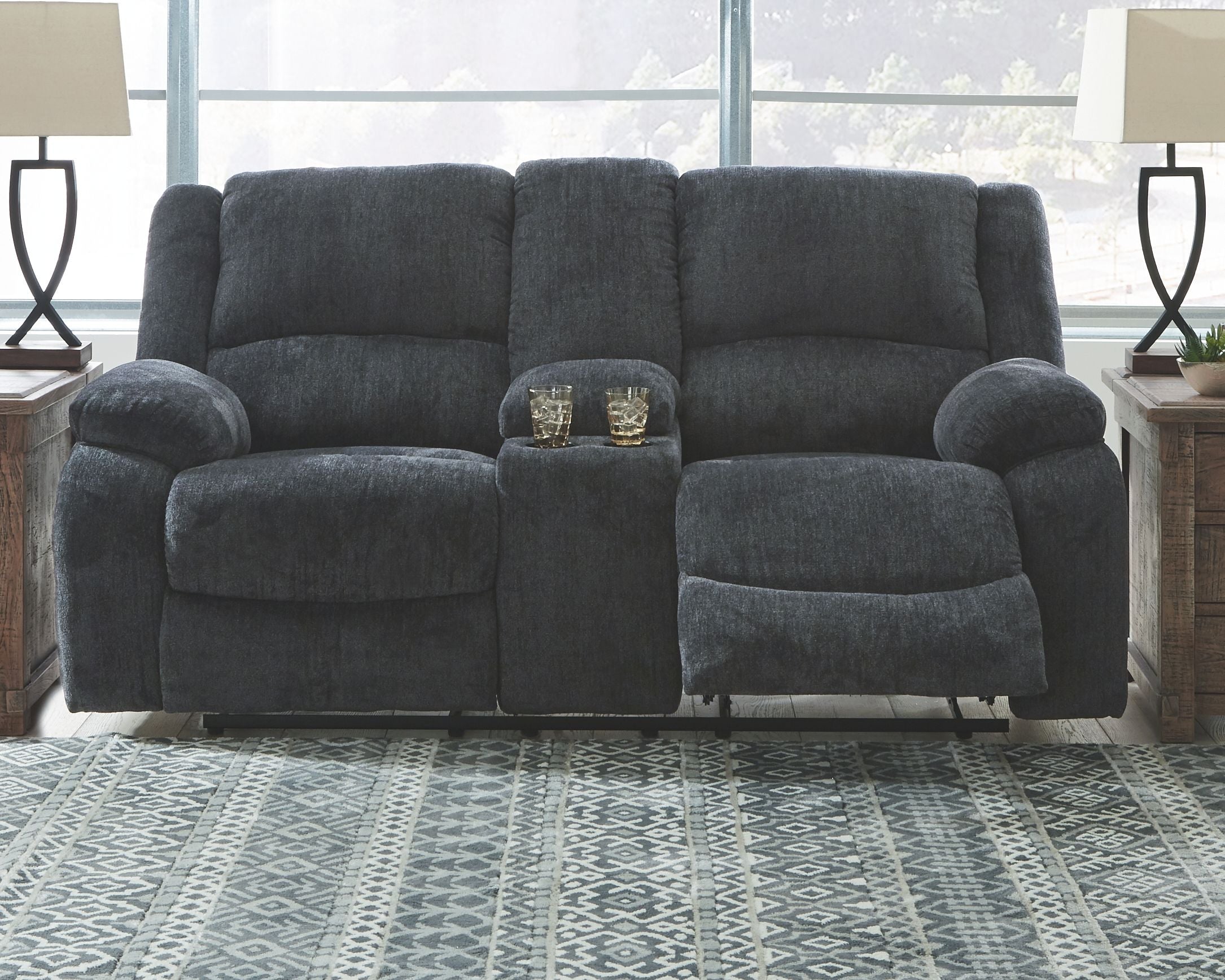 Dark gray reclining loveseat with tall backrest, plush arms, and center console