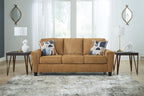 Beige sofa with three seat cushions, patterned pillows, and tapered legs