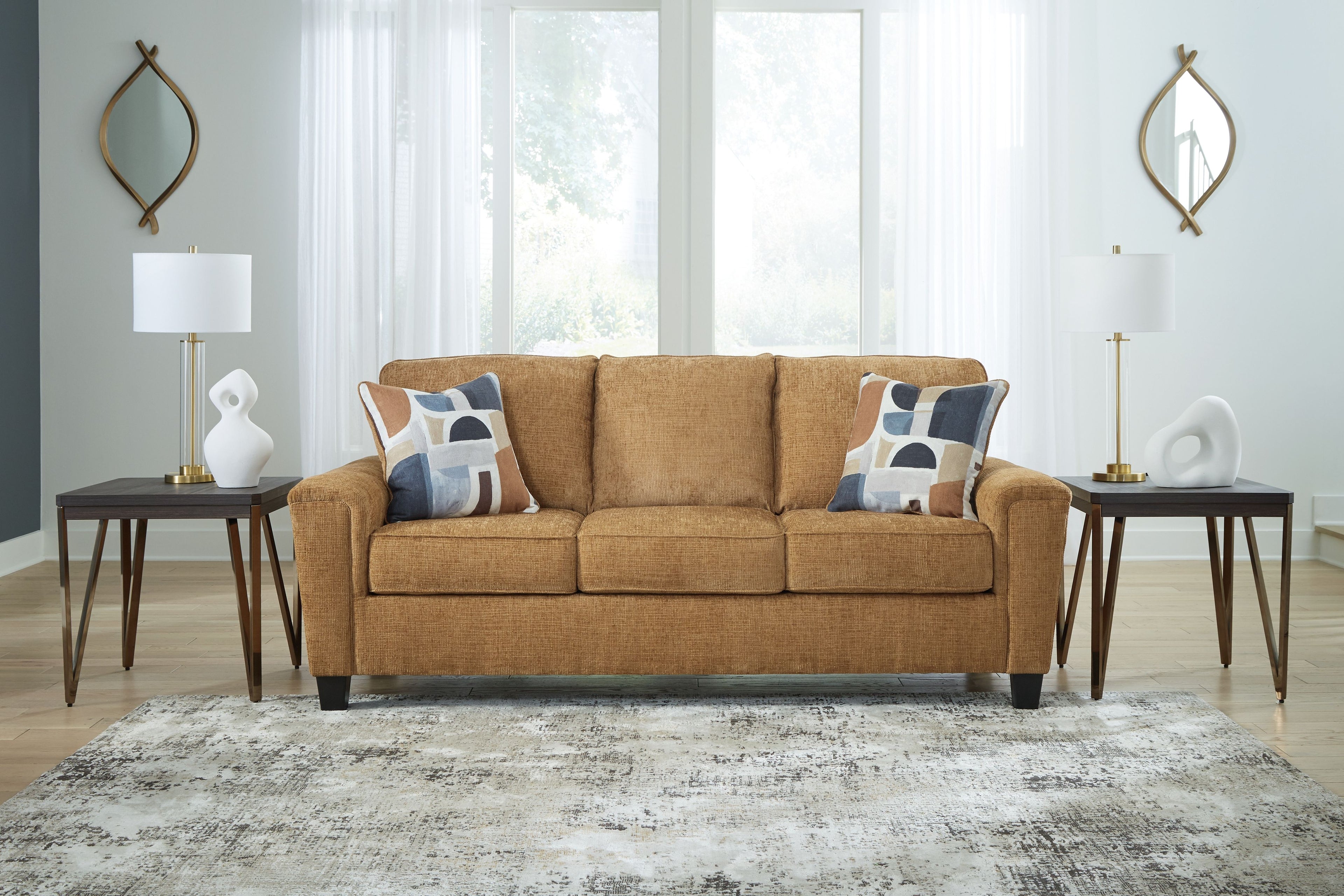 Beige sofa with three seat cushions, patterned pillows, and tapered legs