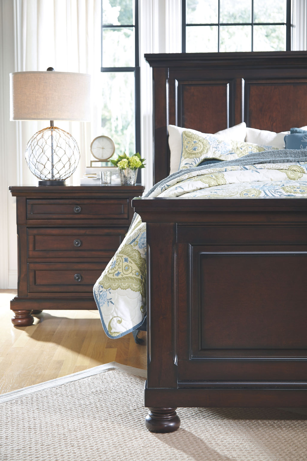 Dark brown bed frame corner with patterned bedding and matching nightstand