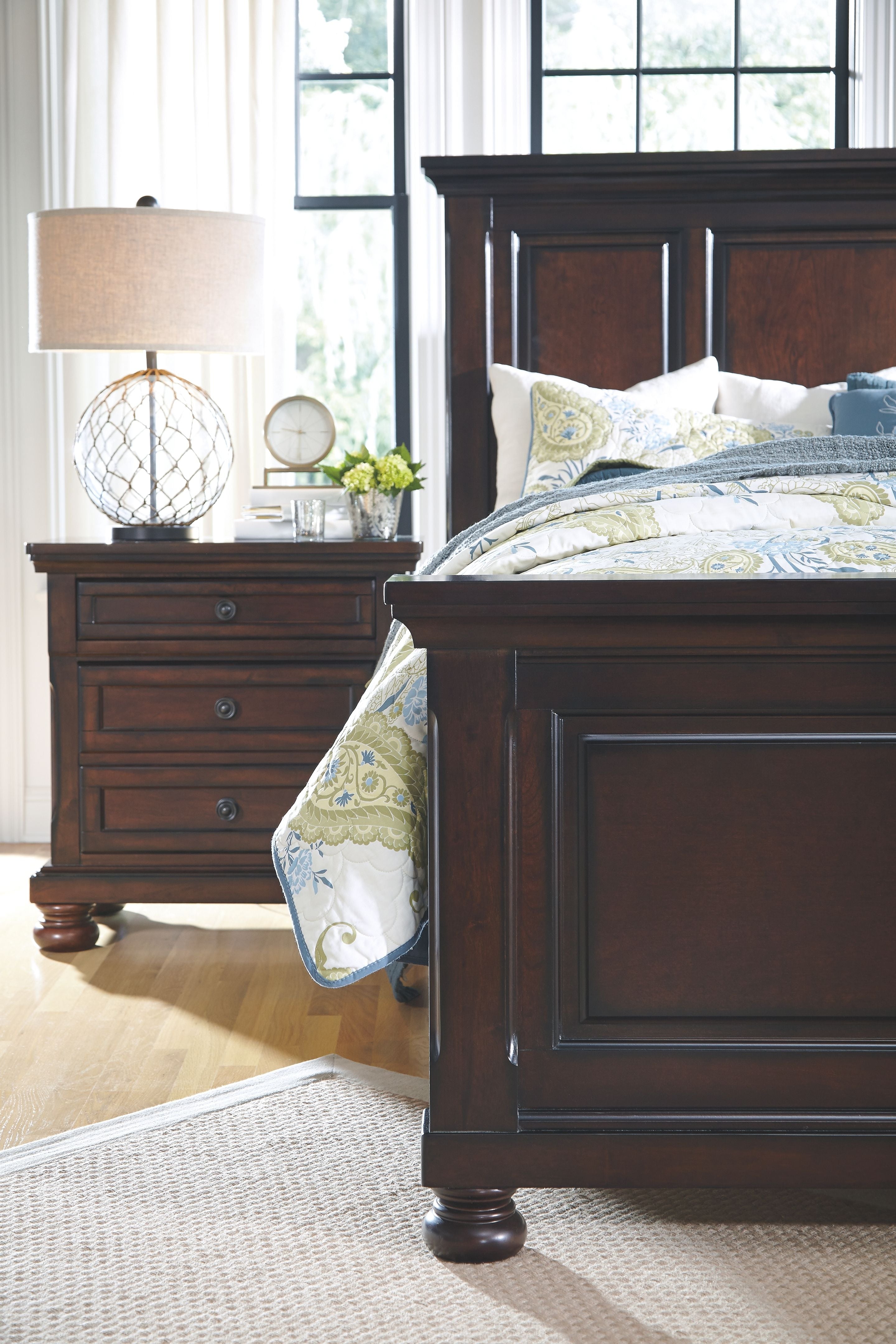 Dark brown bed frame corner with patterned bedding and matching nightstand