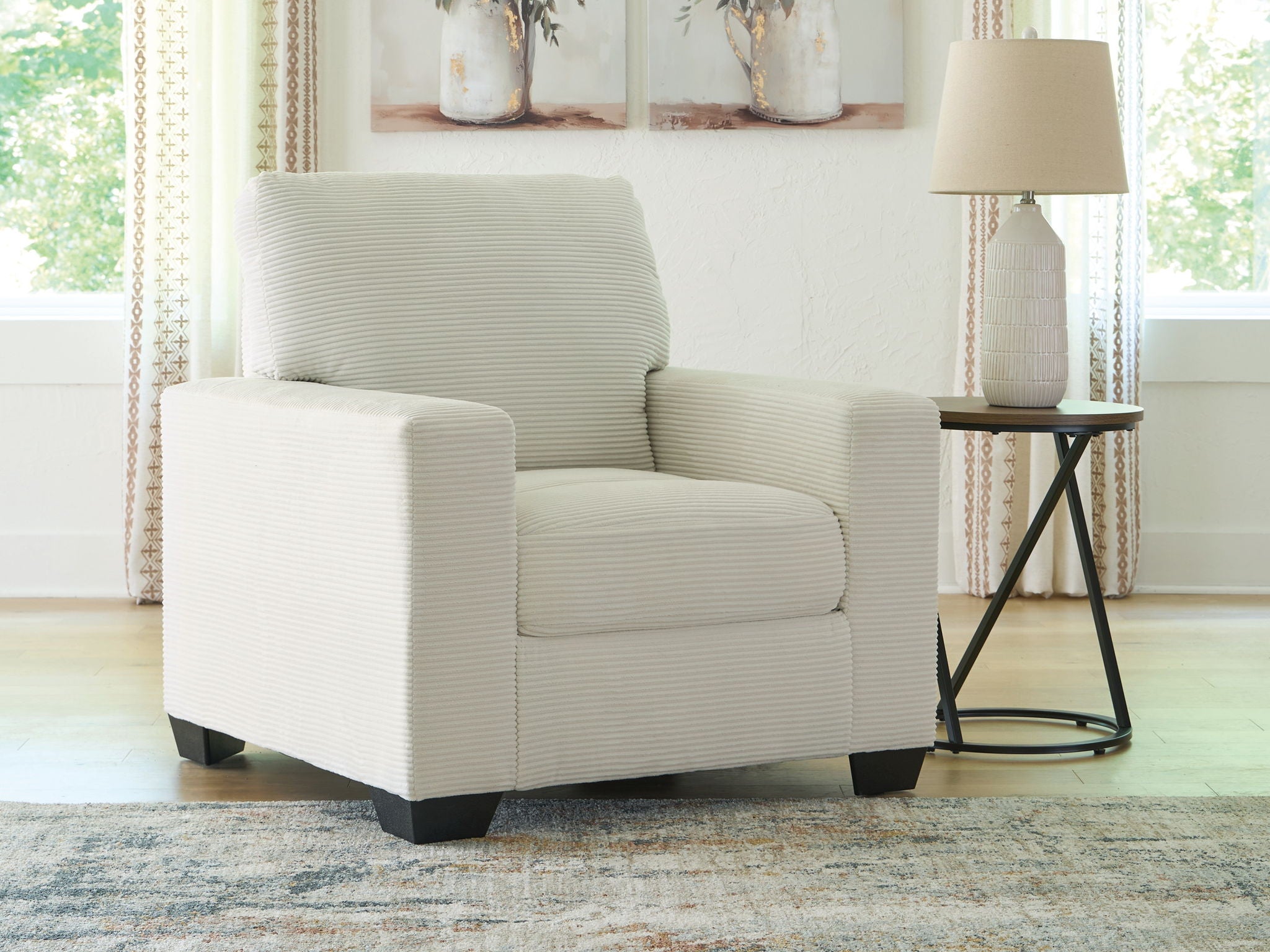 Upholstered armchair with striped upholstery, thick seat cushion, and dark block legs in white.