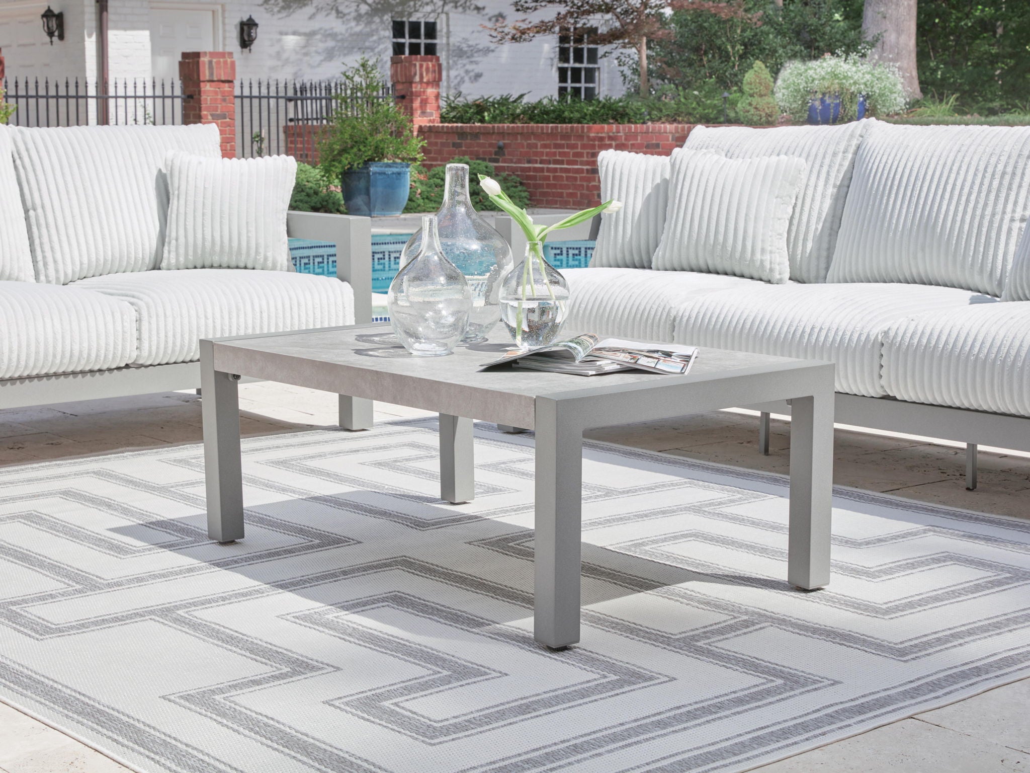 Outdoor gray rectangular table with stone-look top and four legs, with glass decor