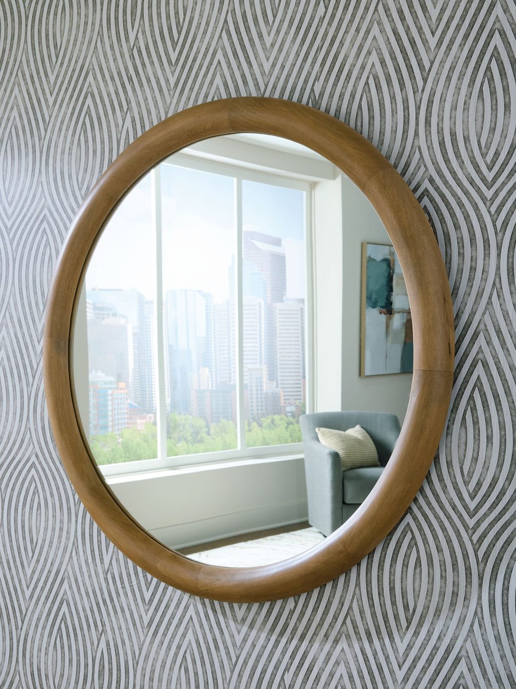 Yadiel brown oval accent mirror with wood-look frame, reflecting a window