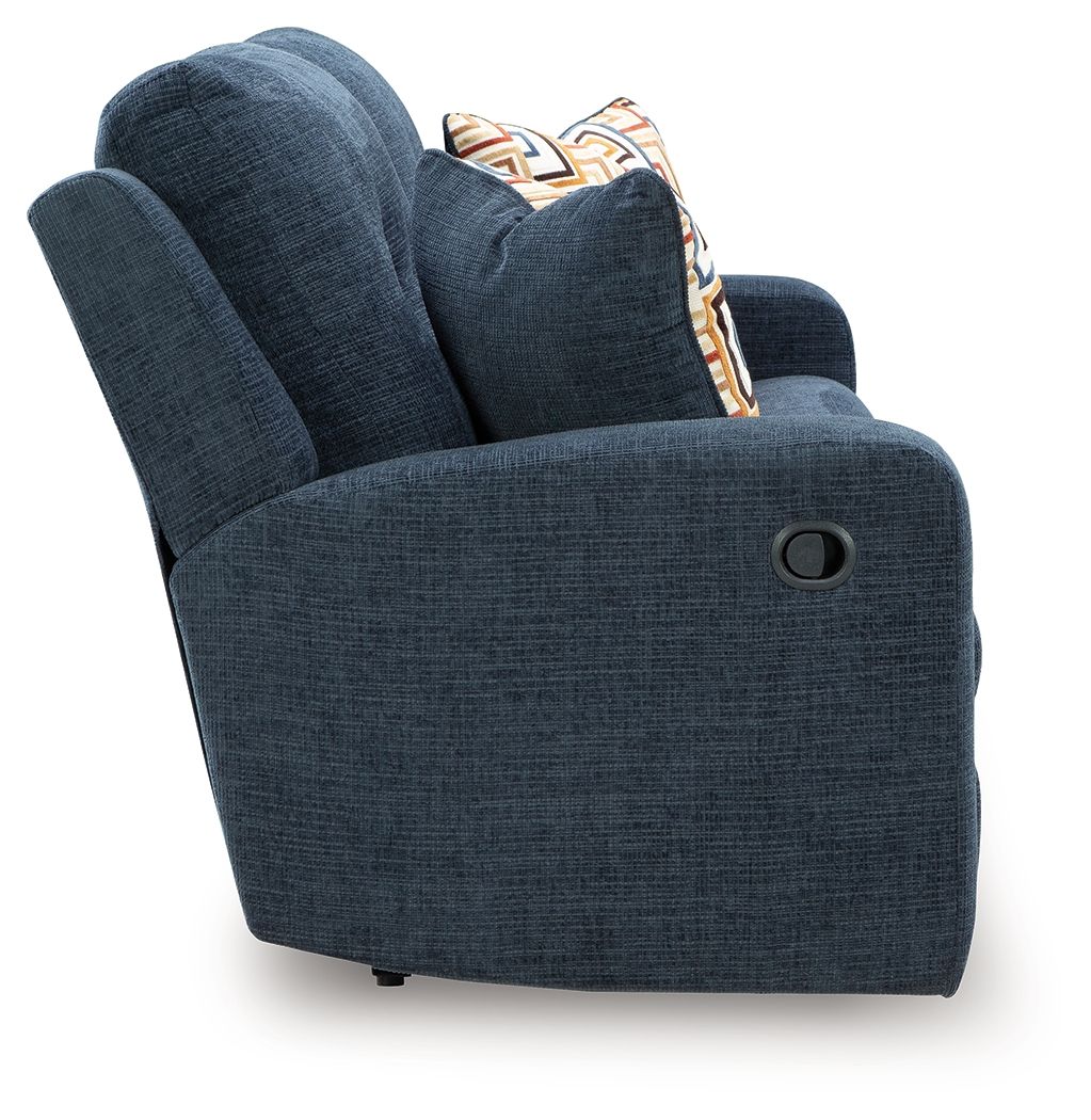Ink blue reclining sofa arm with circular handle detail and patterned pillow on back