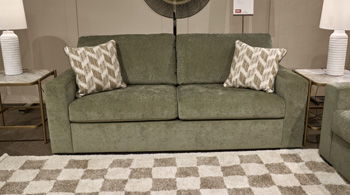 Green fabric sofa with two back cushions and two patterned accent pillows