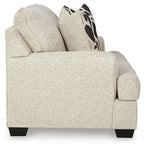 Light beige loveseat side view with rolled arms and two geometric black-and-beige pillows